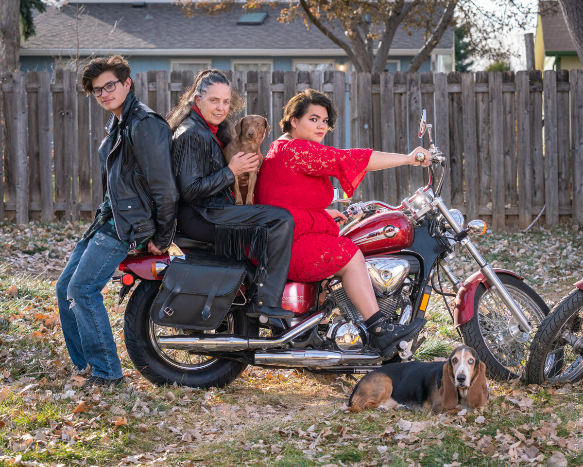 family and dogs on motorcycle in back yard posing for group photo